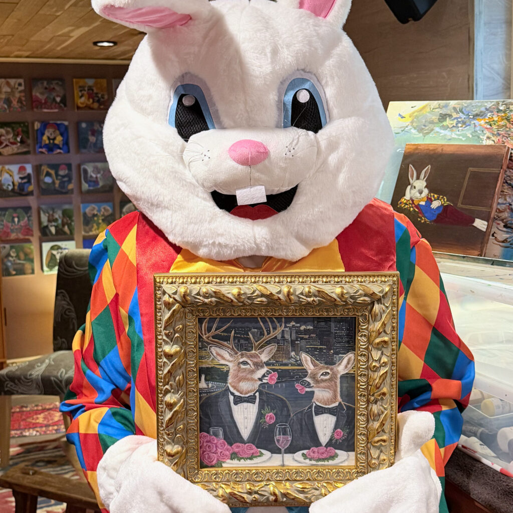 The Bloomin Fool holding an 8x8 inch acrylic painting of a deer in formal attire eating roses against the Pittsburgh skyline.